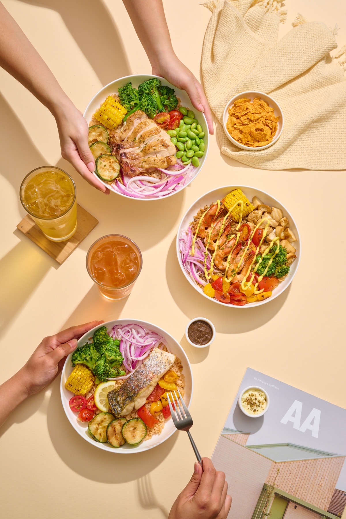 Three friends sharing three OKAO Bowls and drinks at a table